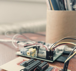 circuit board components, with wires, next to a pencil cup